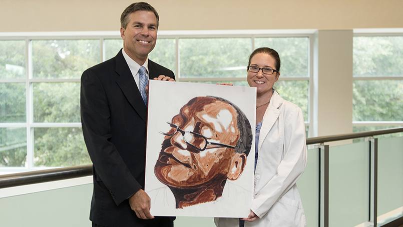Ryan Uitti, M.D., and Beth McAllister with a self-portrait of patient Tyrone Nanton.